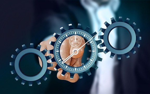 Ein Mann zeigt mit dem Finger auf eine als Zahnrad dargestellte Uhr, die in zwei andere Zahnräder greift.