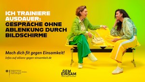 Zwei bunt gekleidete Frauen sitzen auf einer Bank und unterhalten sich angeregt.