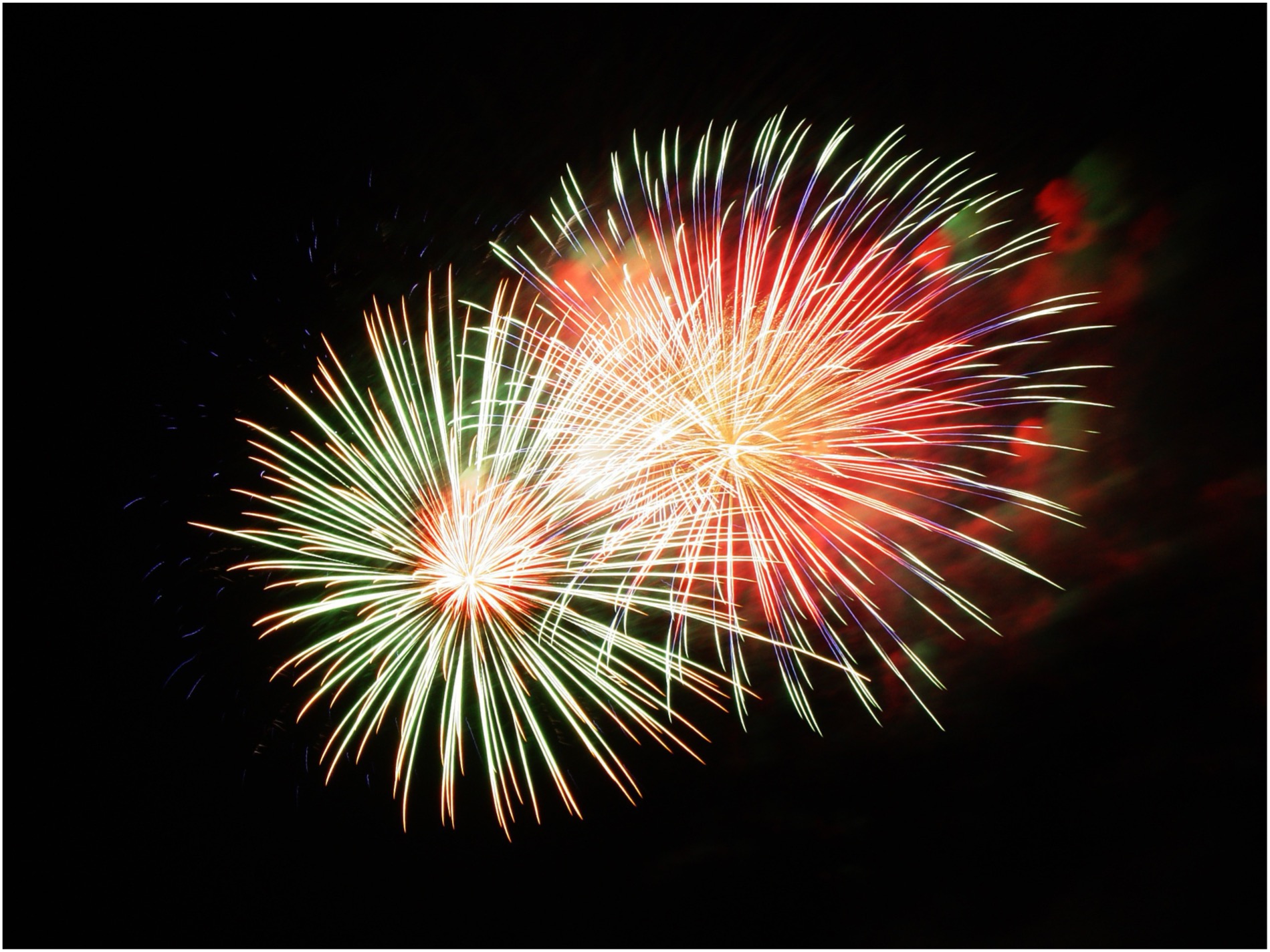 Zusehen ist ein buntes Feuerwerk am dunklen Himmel.